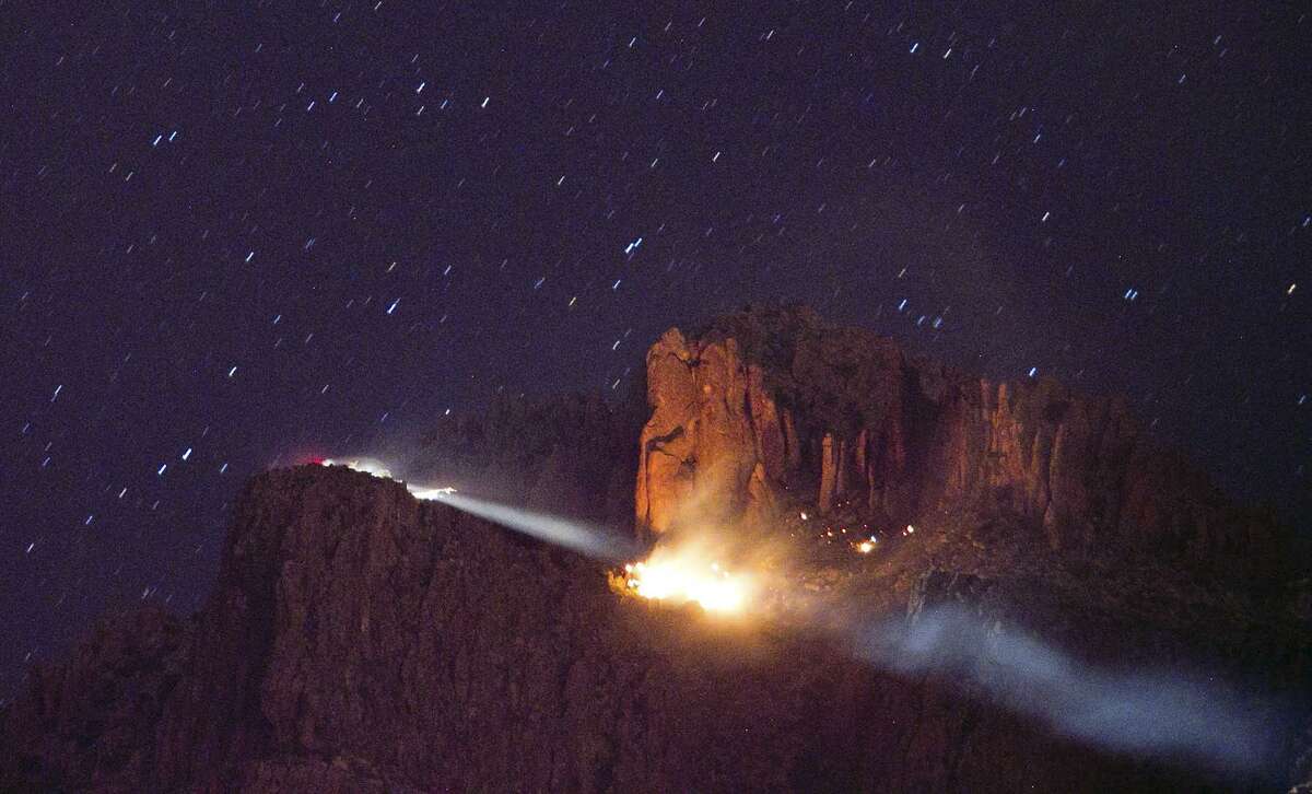 A floodlight, left, is trained on a fire from a small plane crash Wednesday in the Superstition Mountains in Apache Junction, east of Phoenix. Associated Press