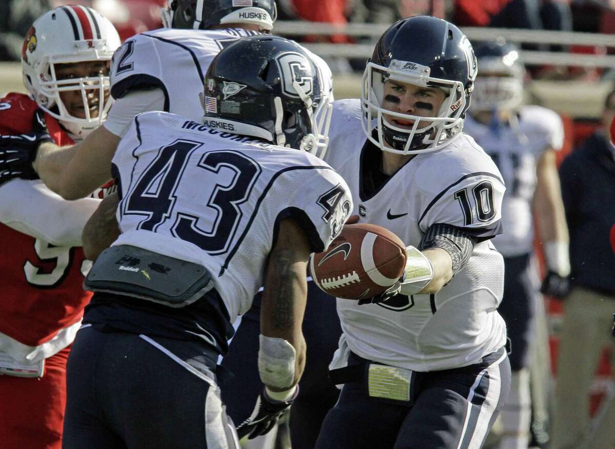 Connecticut quarterback Chandler Whitmer hands off to Lyle McCombs during an NCAA college football game in Louisville, Ky., Saturday, Nov. 24, 2012. (AP Photo/Garry Jones)