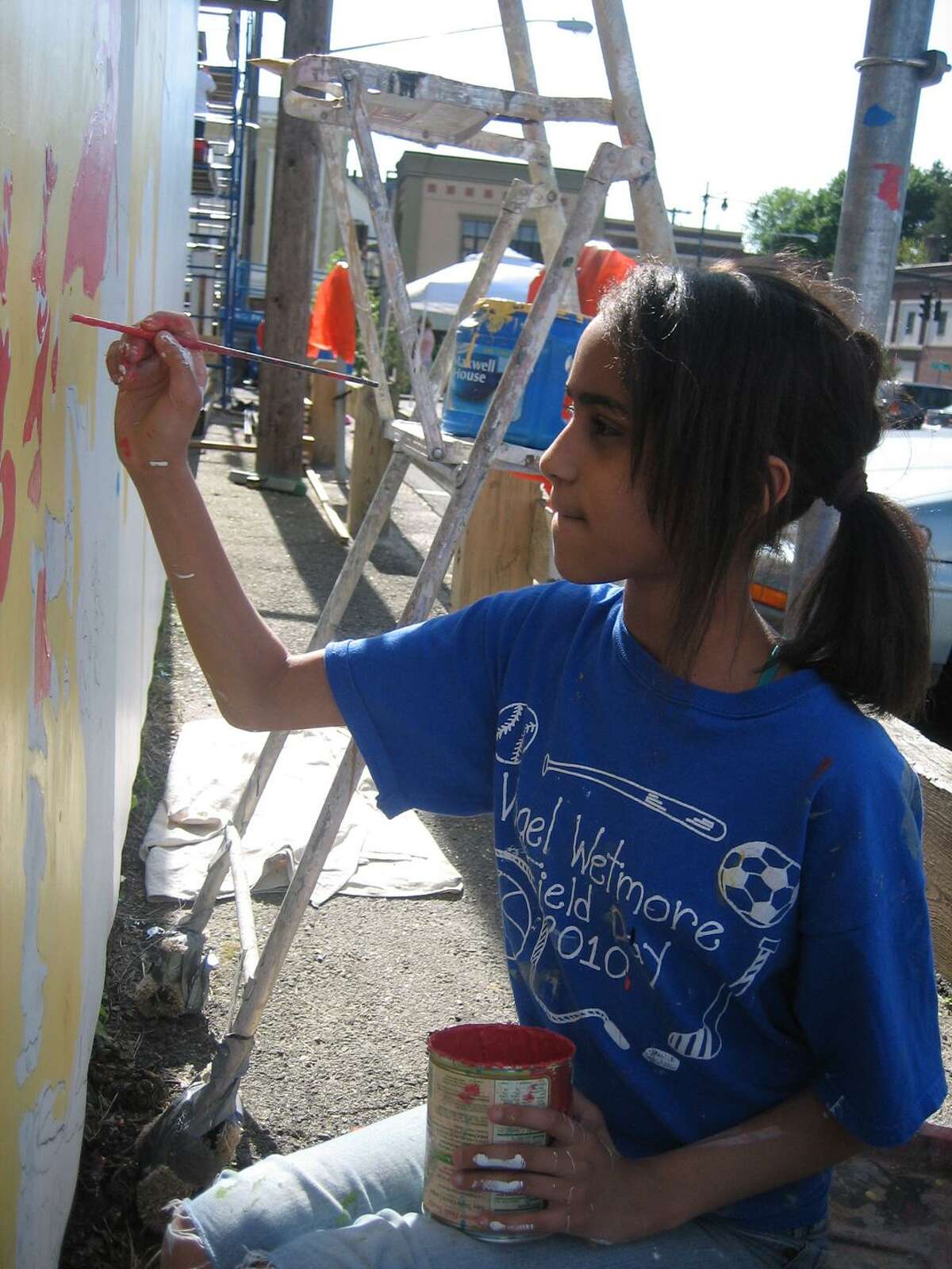 Yasmin Gutierrez paints a portion of a mural that is part of the Community Mural Project being offered by ASAP.