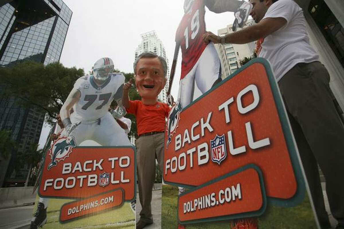 Employees and volunteers for the Miami Dolphins, including one dressed as former coach Don Shula, stand on a downtown Miami street corner Monday, July 25, 2011. NFL players voted to OK a final deal Monday, days after the owners approved a tentative agreement, and the sides finally managed to put an end to the 4O-month lockout, the longest work stoppage in league history. (AP Photo/J Pat Carter)