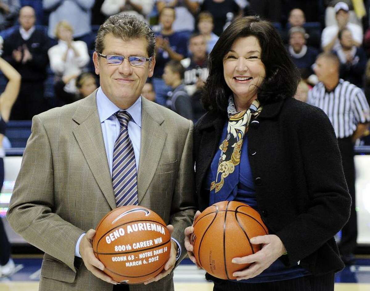 Connecticut senior associate director of athletics Debbie Corum, right, smiles after presenting a commemorative basketball to head coach Geno Auriemma celebrating his 800th career win before his team's NCAA college basketball game against Charleston in Storrs, Conn., Sunday, Nov. 11, 2012. (AP Photo/Fred Beckham)