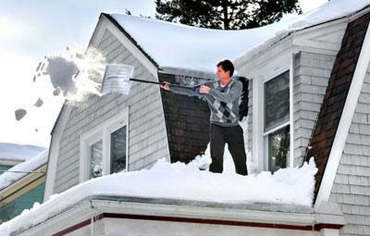 Mike Emmerth clears snow from the roof of his home on West Rock Avenue. (Peter Casolino/Register)