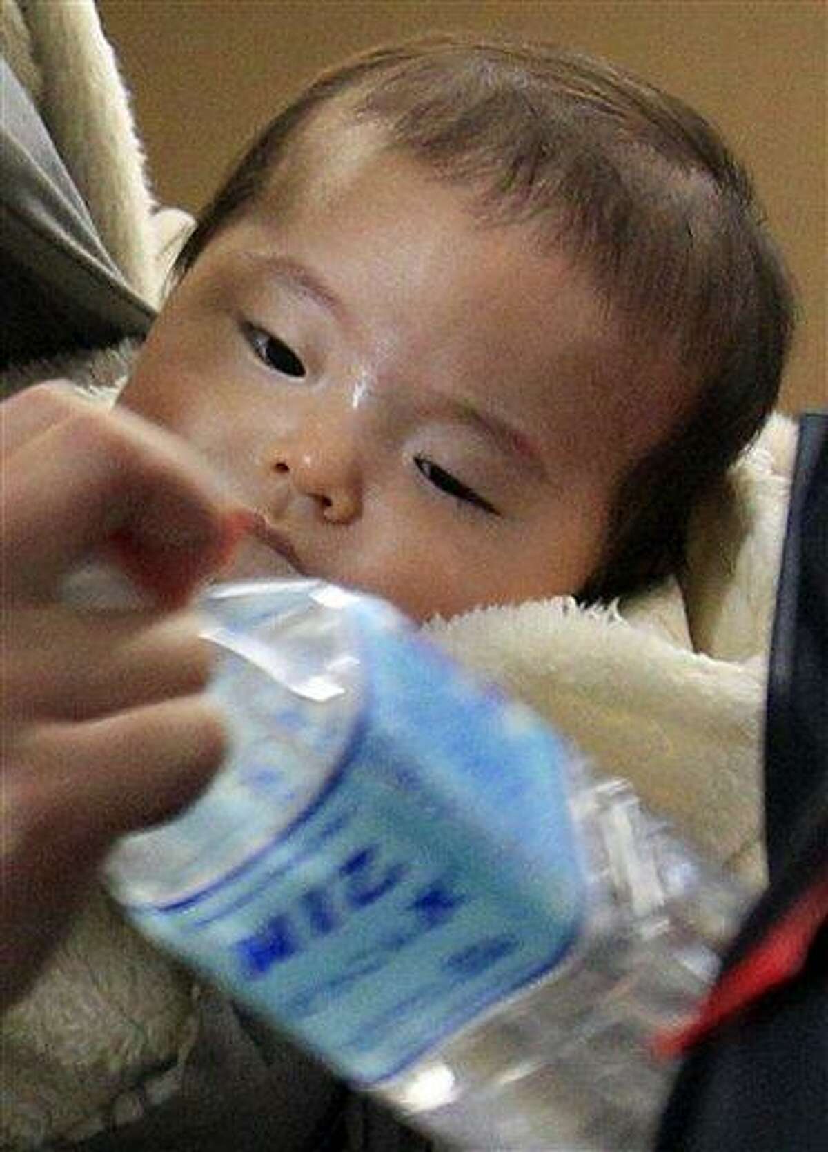 A baby looks at a bottled water as mother receives it at a ward office in Tokyo, Friday, March 25, 2011 as the Tokyo Metropolitan Government started on Thursday to distribute three small bottles of water each to an estimated 80,000 families with babies of 12 months or younger. (AP Photo/ Lee Jin-man)