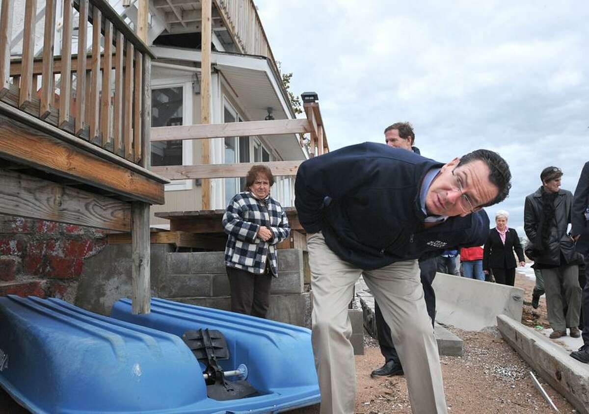 New Haven-- Governor Dannel Malloy looks under a deck at damage in Morris Cove from Hurricane Sandy. Malloy and other government officials visited the area Friday afternoon. Photo--Peter Casolino/New Haven Register. 11/02/12