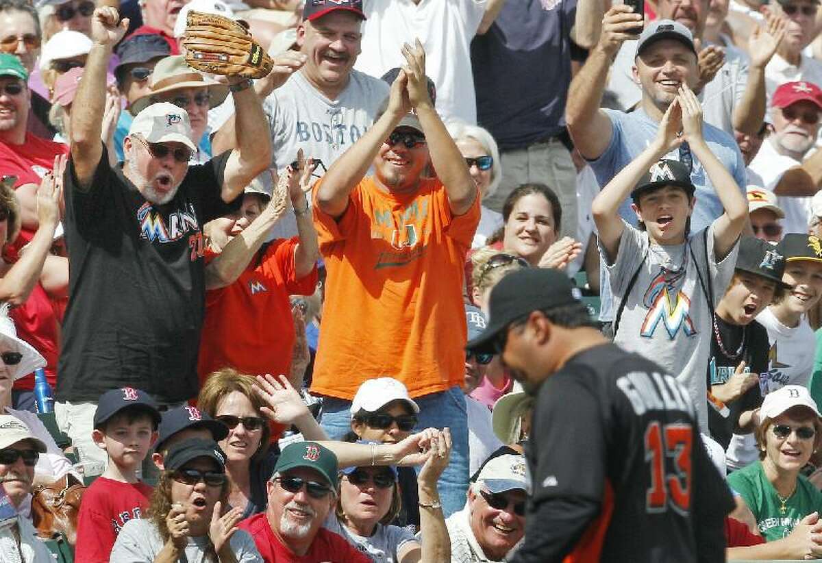 ASSOCIATED PRESS Miami Marlins fans cheer as manager Ozzie Guillen, right, walks off the field after being ejected for arguing a call in the sixth inning of a spring training game against the Boston Red Sox Monday in Fort Myers, Fla