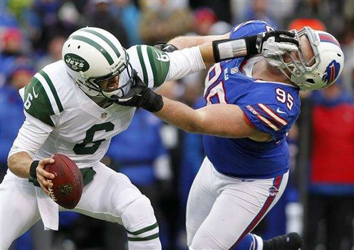 New York Jets quarterback Mark Sanchez (6) holds off Buffalo Bills defensive tackle Kyle Williams (95) during the second half of an NFL football game on Sunday, Dec. 30, 2012, in Orchard Park, N.Y. Buffalo won 28-9. (AP Photo/Bill Wippert)
