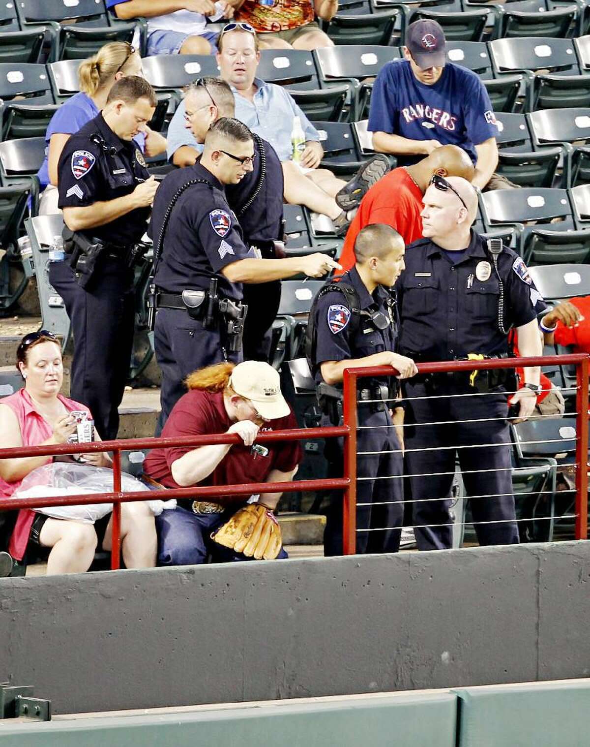 AP PHOTO/THE DALLAS MORNING NEWS/G.J. McCARTHY Arlington Police Department officers gather near where a Texas Rangers fan fell about 20 feet onto concrete reaching out for a baseball tossed his way by All-Star outfielder Josh Hamilton during a game between the Rangers and Oakland Athletics, Thursday night in Arlington, Tx. Shannon Stone, a 39-year-old firefighter from Brownwood, died at a hospital Thursday night, the Tarrant County Medical Examiner's Office said.