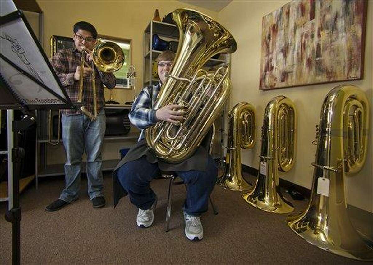 In this recent photo, University of Redlands students -- trombonist Ben Solis 28, left, and master tuba player Victor Mortson, 23 -- play their instruments at The Horn Guys store in La Crescenta, Calif. Someone who is breaking into high schools from the East Side of Los Angeles to the shores of Manhattan Beach and stealing expensive tubas to supply a fast-growing banda black market. Associated Press