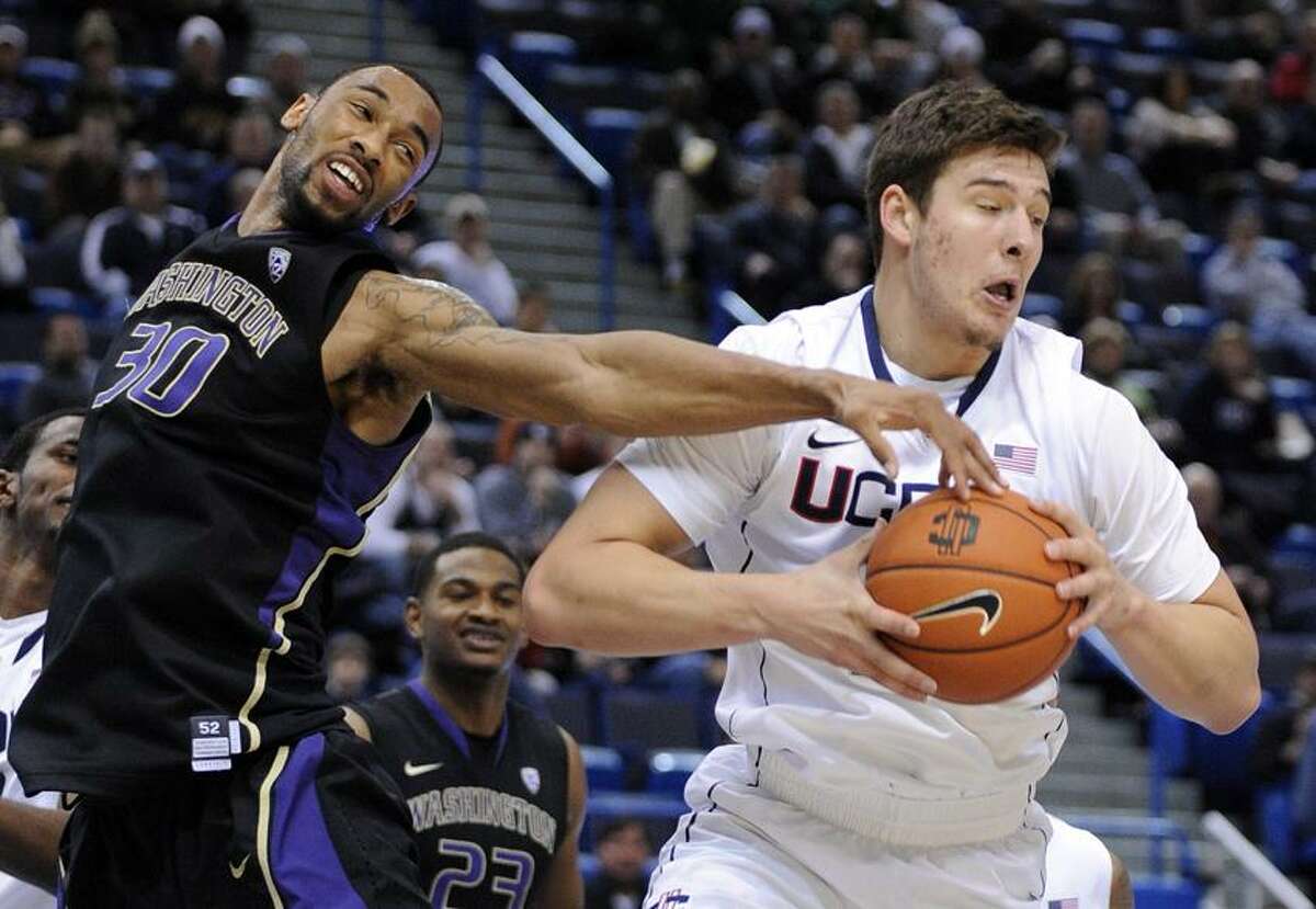 Connecticut's Tyler Olander, left, grabs a rebound from Washington's Desmond Simmons during the first half of an NCAA college basketball game in Hartford, Conn., Saturday, Dec. 29, 2012. (AP Photo/Fred Beckham)