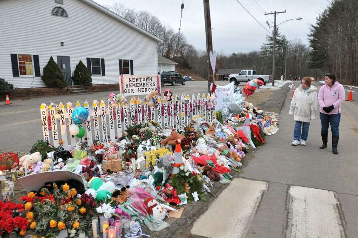 Tami Lawson, right, and her mother, Penny Tanner look at the memorials Wednesday along the driveway of the Sandy Hook Elementary School. Lawson grew up in Newtown and now lives in Golden, Colorado. Her mother still lives in Newtown. Peter Casolino/Register