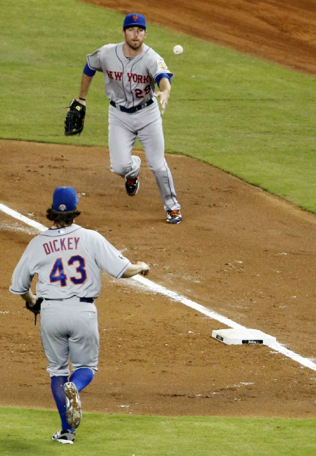 ASSOCIATED PRESS New York Mets first baseman Ike Davis (29) tosses the ball to starting pitcher R.A. Dickey (43) to put out Miami Marlins' Rob Brantly at first base during the third inning of Friday night's game in Miami. The Mets won 3-0.