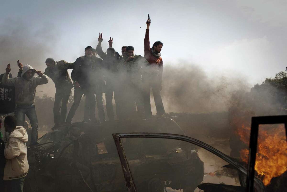 Libyan rebels celebrate on top of burning cars after Libyan leader Moammar Gadhafi's forces where pushed back from Benghazi, eastern Libya, Saturday, March 19, 2011. Explosions shook the Libyan city of Benghazi early on Saturday while a fighter jet was heard flying overhead, and residents said the eastern rebel stronghold was under attack from Moammar Gadhafi's forces. (AP Photo/Anja Niedringhaus)