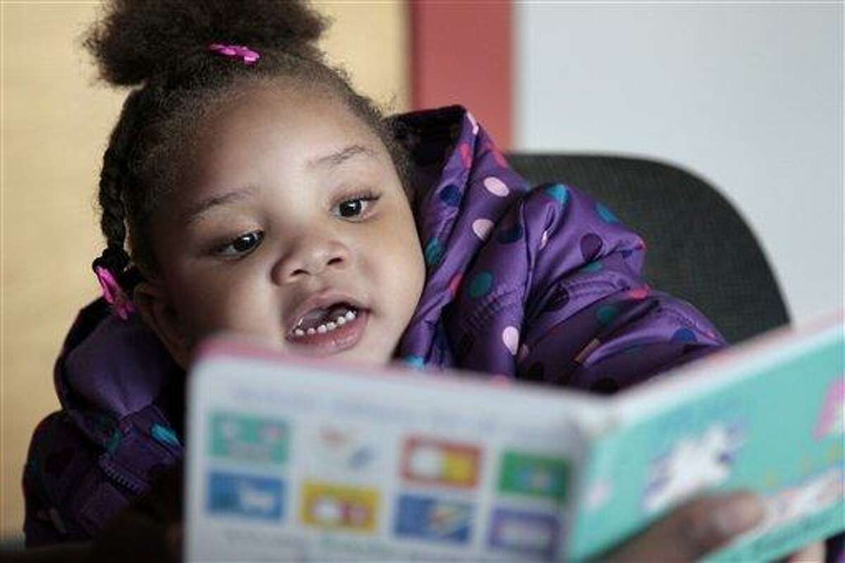 In this photo taken Dec. 8, 2011, Taliyah Garrett, 3, looks at a book as she gets help in learning to read by a coordinator from the Parent Child Home Program during a visit in Seattle. The home visiting program, supported by United Way of King County, Wash., helps children from low-income families prepare for kindergarten by tutoring parents in how to teach their children. Many of the nation's nonprofit organizations are digging in for another three to four years of financial distress, according to researchers who keep an eye on the charitable world. Associated Press