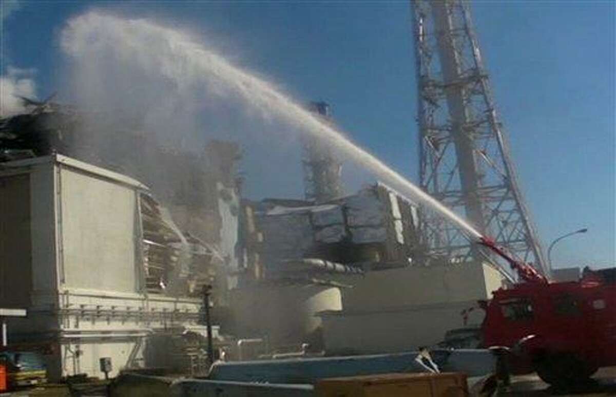 In this image taken from footage released by the Japan Defense Ministry, a fire engine from the Japan Self-Defense Forces sprays water toward Unit 3 of the troubled Fukushima Dai-ichi nuclear complex on Friday, March 18, 2011. In the backgrounds is Unit 4. Military fire trucks sprayed the reactor units Friday for a second day, with tons of water arching over the facility in attempts to prevent the fuel from overheating and emitting dangerous levels of radiation. (AP Photo/Japan Defense Ministry) EDITORIAL USE ONLY