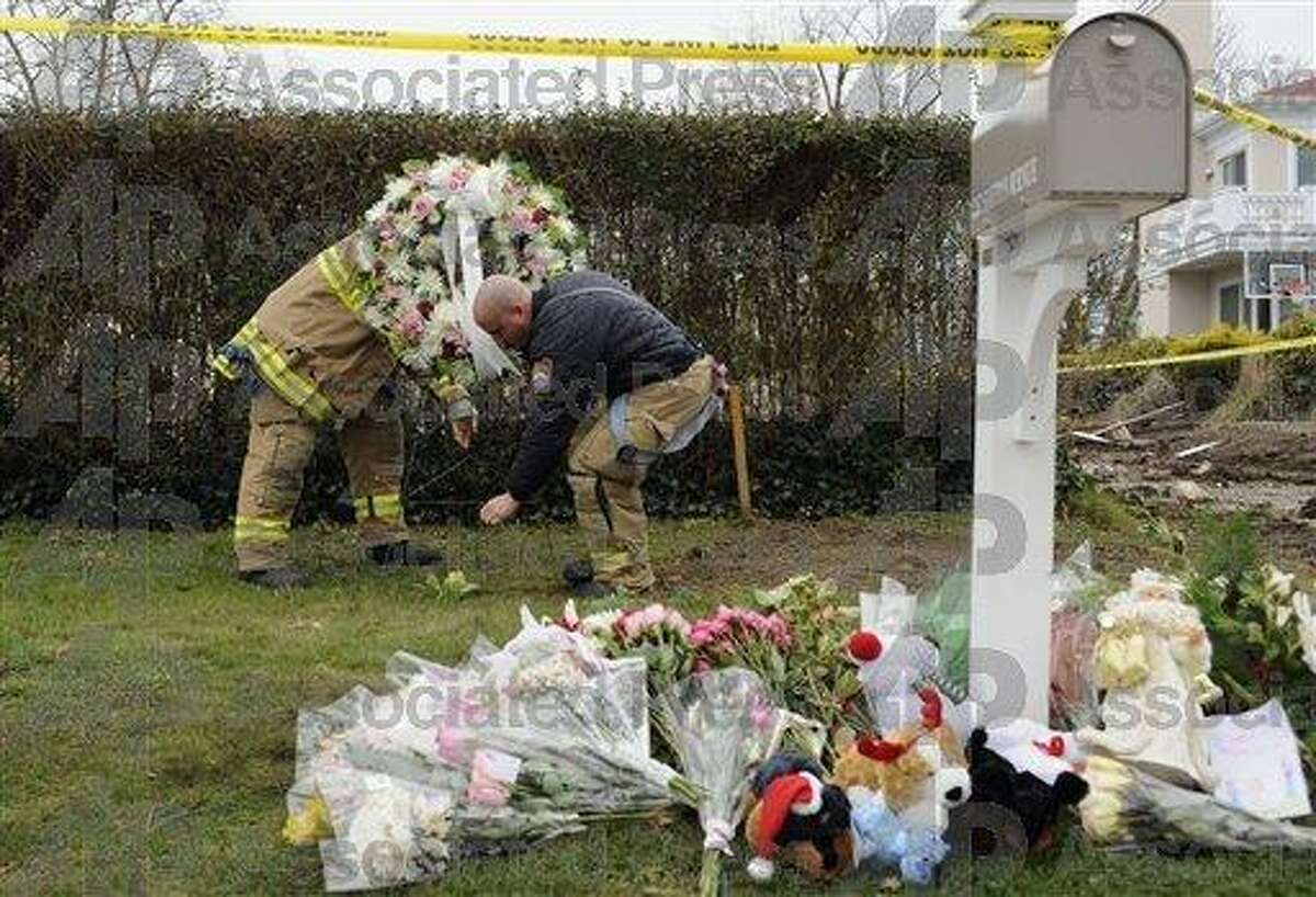 Firefighters adjust the position of a wreath that was part of a memorial at Stamford fire that claimed five lives on Christmas Day 2011. (AP)