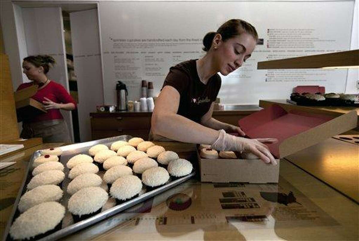 Sprinkles Cupcakes employee Sara Cebulski, right, arranges a custom box of cupcakes at Sprinkles in Beverly Hills, Calif. Associated Press