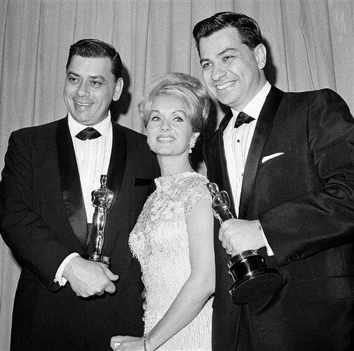 In this 1965 file photo, actress Debbie Reynolds poses with Academy Awards winners for best music Richard M. Sherman, right, and Robert Sherman, left, who received the award for "Mary Poppins" in Santa Monica Calif. Songwriter Sherman, who wrote the tongue-twisting "Supercalifragilisticexpialidocious" and other enduring songs for Disney classics, has died. He was 86. Associated Press