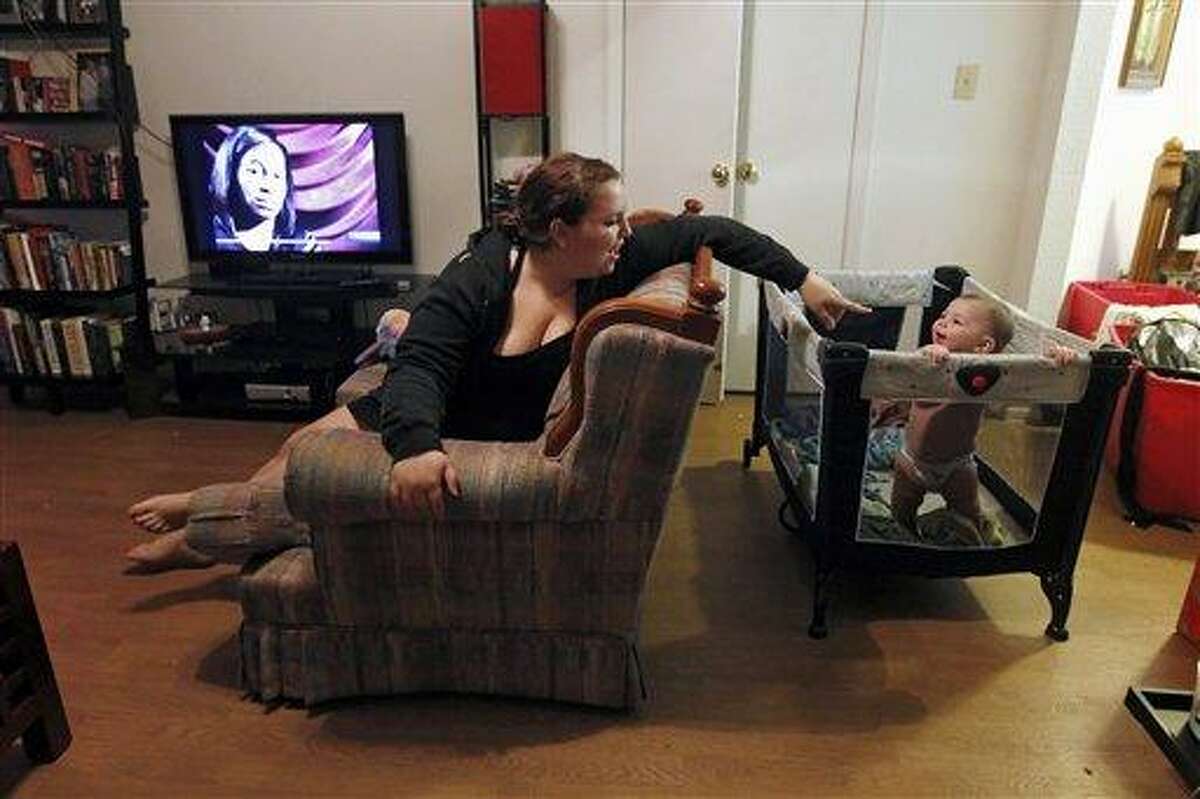 EMBARGOED UNTIL 12:01 A.M. EST, THURSDAY, DEC. 15 - Zenobia Bechtol, 18, and her seven-month-old baby girl Cassandra play in the living room of her mother's apartment in Austin, Texas, Friday, Dec. 14, 2011, after he and her boyfriend were evicted from their apartment after he lost his job. Squeezed by rising living costs, a record number of Americans _ 1 in 2 _ have now fallen into poverty or are scraping by on earnings that classify them as low-income. The latest census data paint a bleak picture of a shrinking middle class amid persistently high unemployment and a fraying government safety net. (AP Photo/Erich Schlegel)