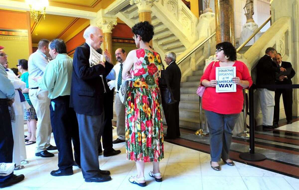 Union members wait outside \Senate chambers while lawmakers meet in caucus at the state Capitol in Hartford Thursday. At right with sign is Deanna Chaparro, treasurer of AFSCME Local 538. Arnold Gold/Register