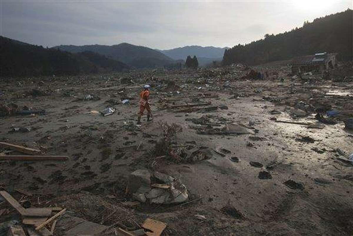 A Japanese rescue team member walks through the completely leveled village of Saito in northeastern Japan Monday, March 14, 2011. Rescue workers used chain saws and hand picks Monday to dig out bodies in Japan's devastated coastal towns, as Asia's richest nation faced a mounting humanitarian, nuclear and economic crisis in the aftermath of a massive earthquake and tsunami that likely killed thousands. (AP Photo/David Guttenfelder)