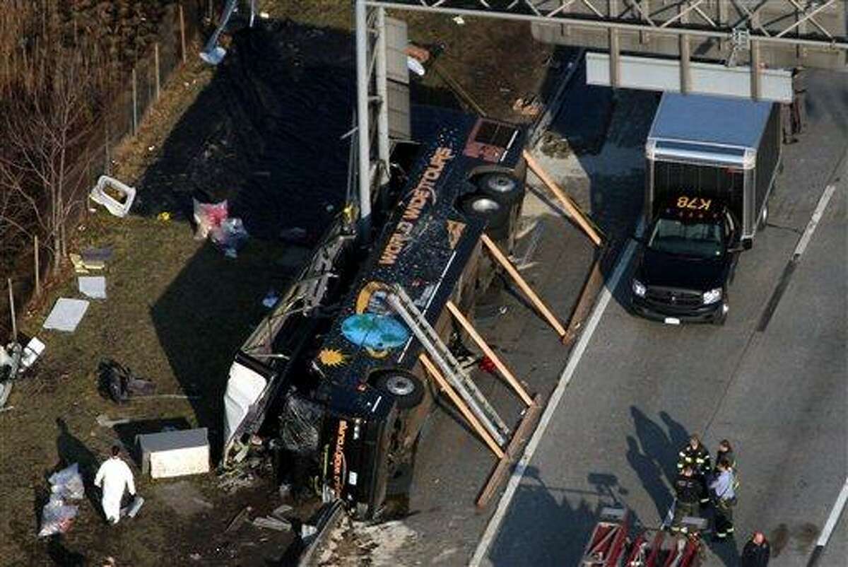 Emergency personnel respond to the bus crash on Interstate 95 in the Bronx borough of New York, Saturday, March 12, 2011. At least 14 people died when the bus, returning to New York from a casino in Connecticut, flipped onto its side and was sliced in half by the support pole for a large sign.(AP Photo/The Journal News, Frank Becerra Jr.)