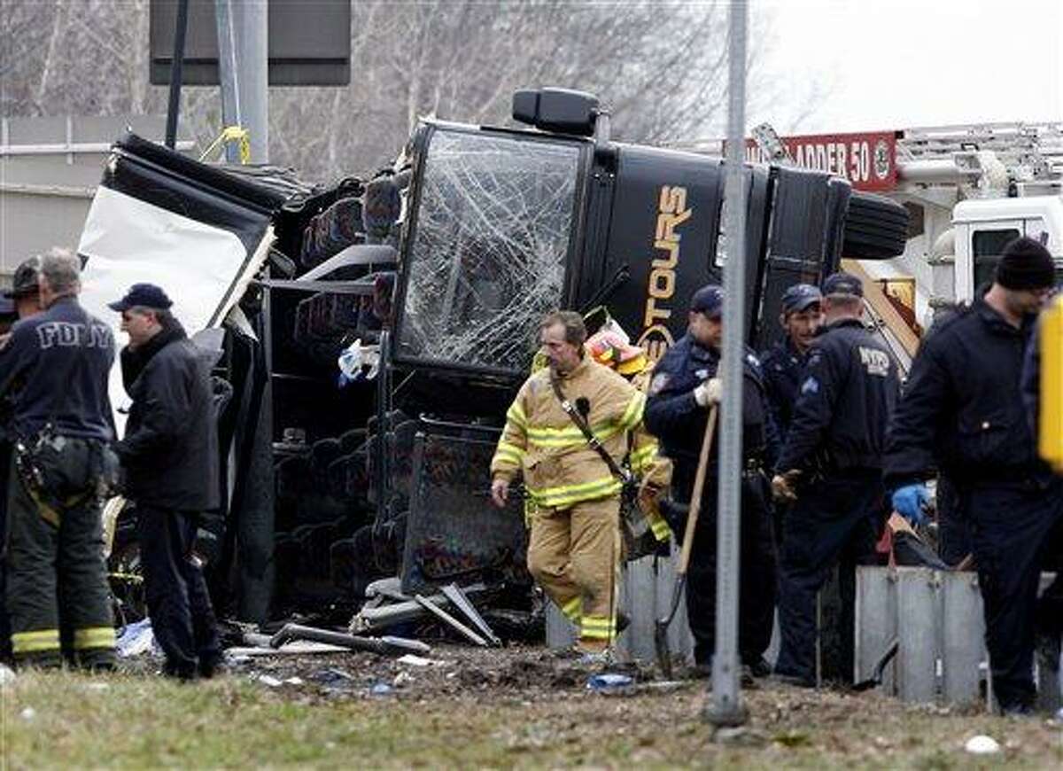 Emergency personnel investigate the scene of a bus crash on Interstate-95 in the Bronx borough of New York Saturday, March 12, 2011. Thirteen people died when the bus, returning to New York from a casino in Connecticut, flipped onto its side and was sliced in half by the support pole for a large sign. (AP Photo/David Karp)
