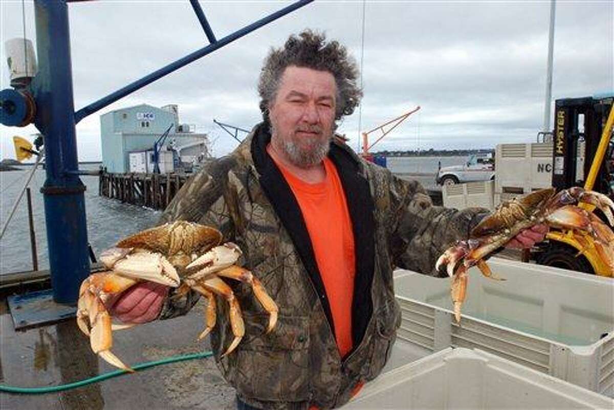 Kevin Wilson, manager of Nor-Cal Seafood, Inc., holds up a pair of Dungeness crabs, landed by local fishermen, Saturday, March 12, 2011, at Crescent City, Calif. As their boat basin was pounded by surges from a tsunami, fishermen struggled to find some normalcy amid the devastation, and some landed small catches of crab. (AP Photo/Jeff Barnard)