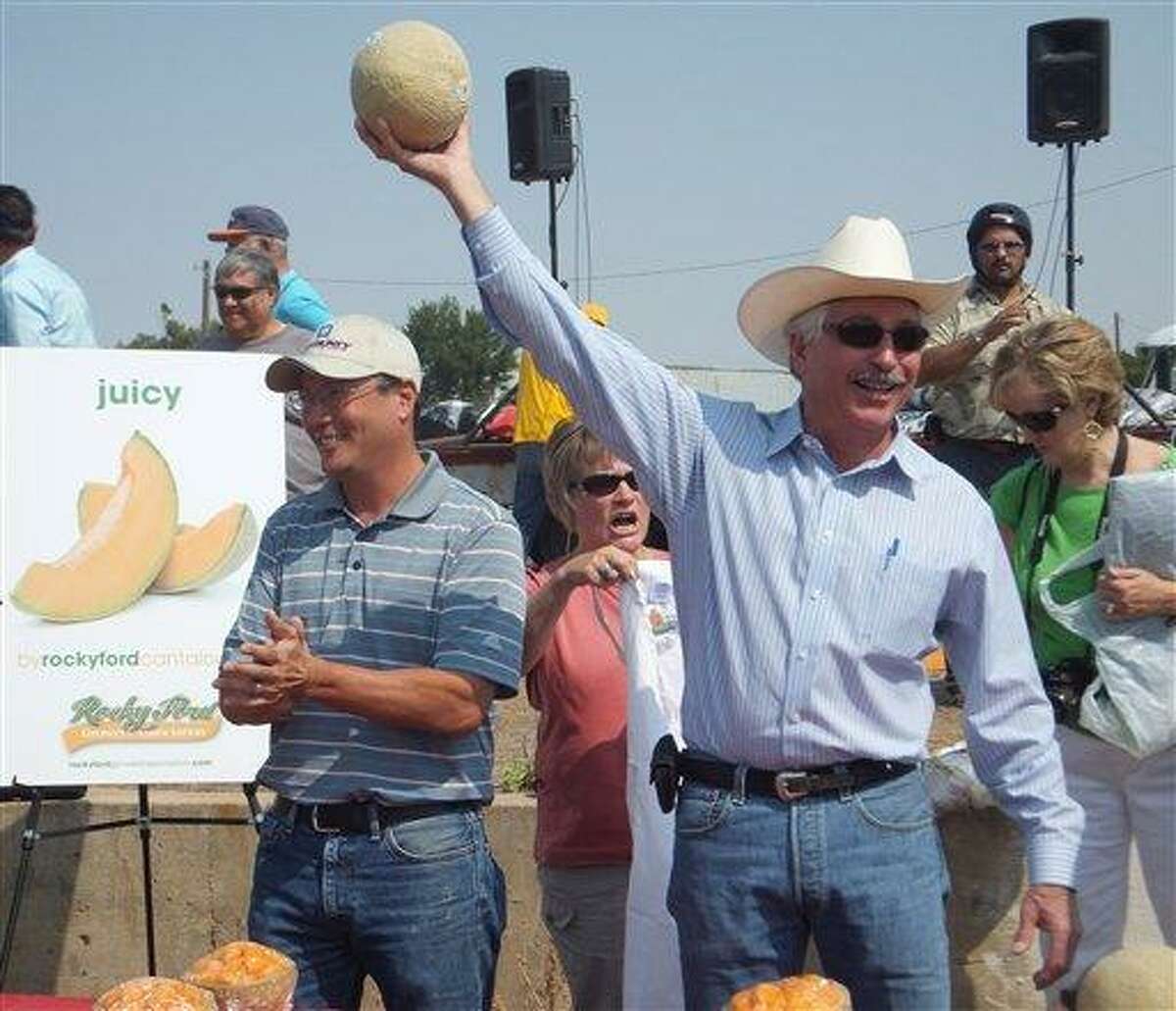 Colorado Agriculture Secretary John Salazar, right, holds up a Rocky Ford cantaloupe and declares it "the sweetest, best melon in the country" at the Arkansas Valley Fair in Rocky Ford, Colo., Saturday. A year after melons from southeast Colorado were the source of a nationwide listeria outbreak that killed 30 and sickened hundreds, growers in Rocky Ford have spent nearly $1 million in safety upgrades and say they're having a strong season with higher prices and strong demand. (AP Photo/Kristen Wyatt)