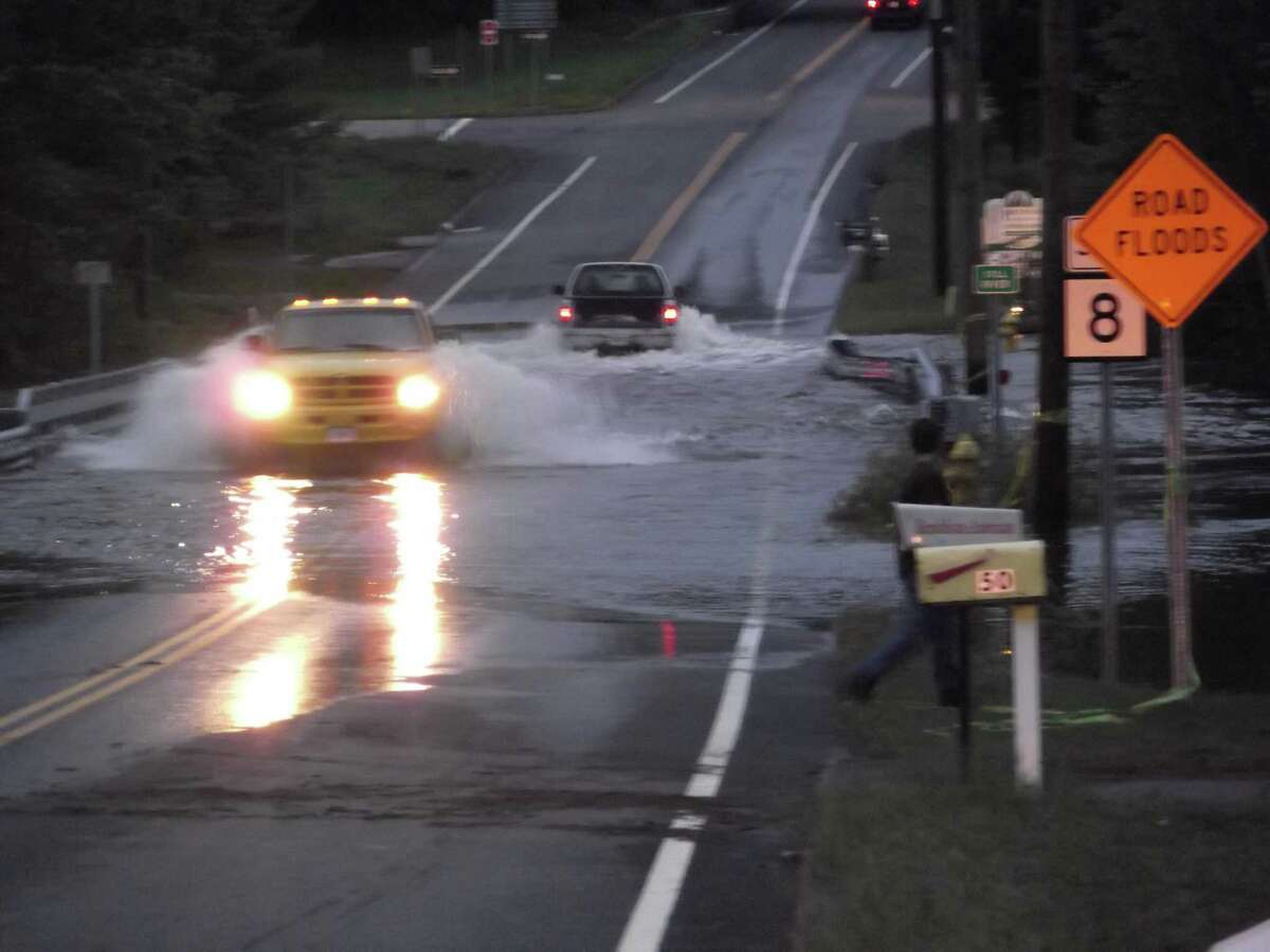 Drivers cross the Still River overflow on Pinewoods Road despite warnings to avoid driving on flooded roads.