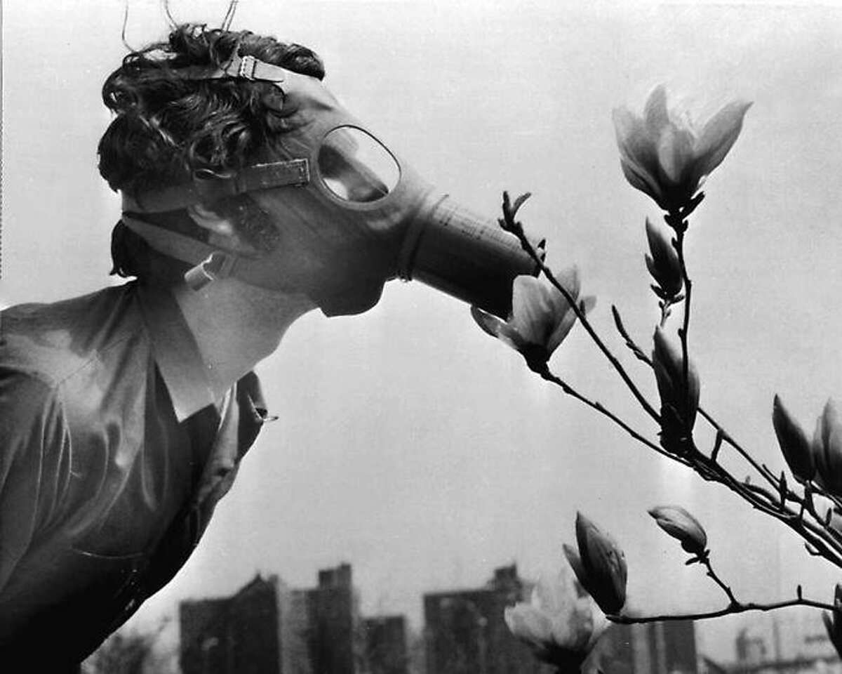 A Pace College student in a gas mask "smells" a magnolia blossom in City Hall Park on Earth Day, April 22, 1970, in New York. Associated Press