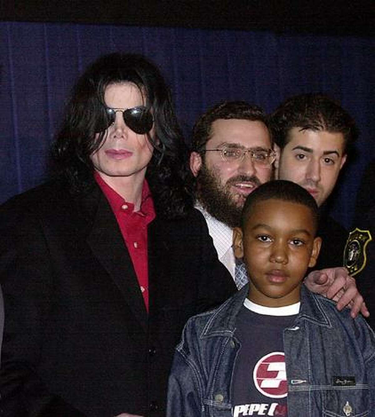 FILE - In this March 25, 2001 file photograph, pop icon Michael Jackson, center, and Rabbi Schmuley Boteach, pose with a child and an unidentified man at the Loew's Metroplex theatre in Newark, N.J., at the kickoff of Jackson's" Heal The Kids" program designed to promote quality time between parents and children. A new book, "The Michael Jackson Tapes," by Boteach, Michael Jackson's former spiritual adviser says the pop superstar feared the ravages of old age and appeared to be abusing prescription drugs and cosmetic surgery nearly a decade before his death. (AP Photo/Warren Westura, File)