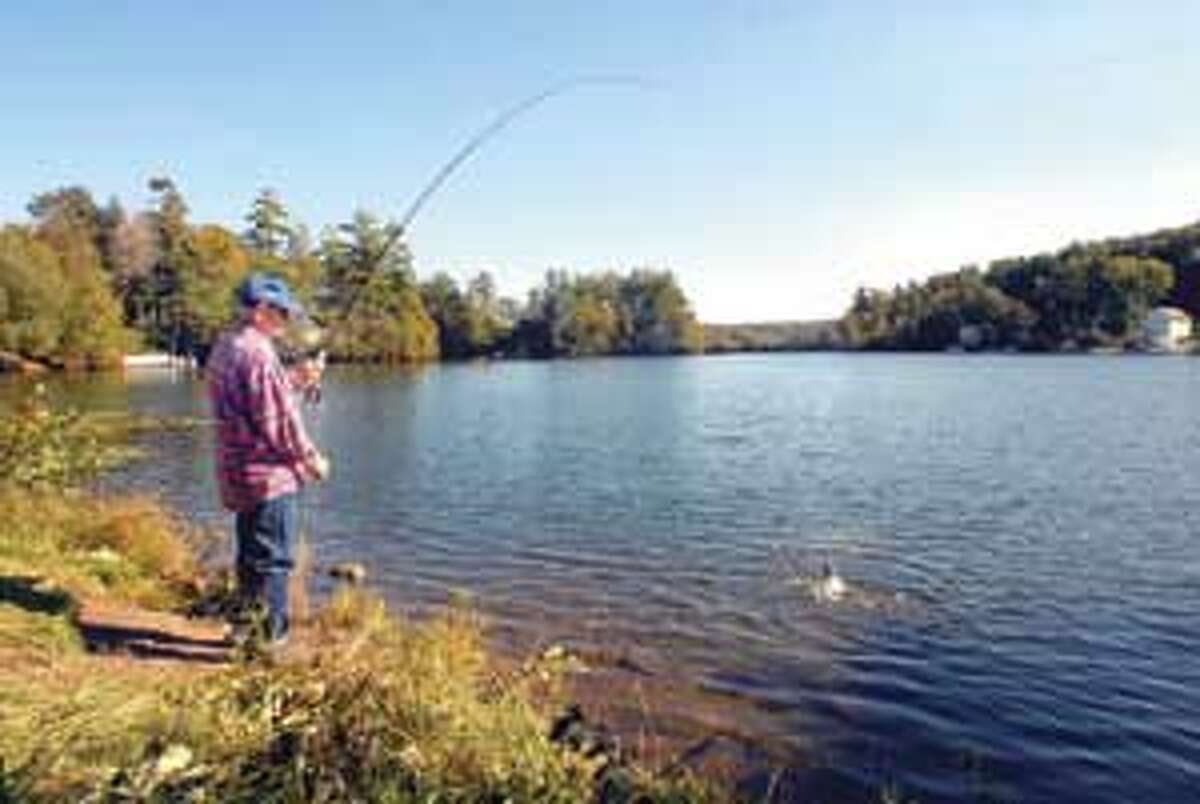 Joseph Royer snags a brown trout out of Highland Lake in Winsted Monday, while enjoying the last full day of summer. Mic Nicosia/Register Citizen
