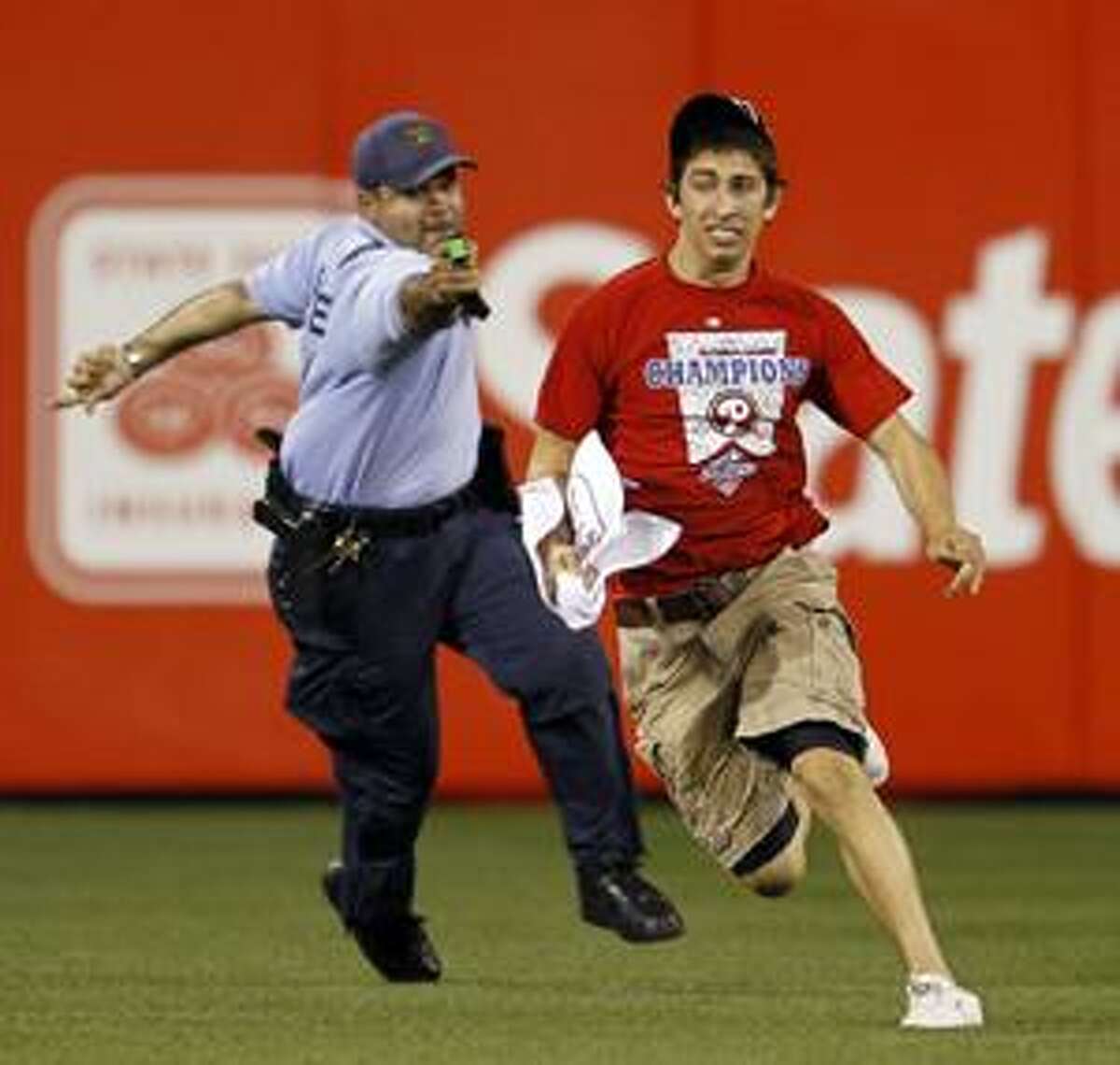 In this photo taken on May 3, 2010, a law enforcement officer chases down Steve Consalvi after he ran onto the field before the eighth inning of a baseball game between the Philadelphia Phillies and the St. Louis Cardinals in Philadelphia. The police officer used a Taser gun to apprehend Consalvi. (AP Photo/Matt Slocum)