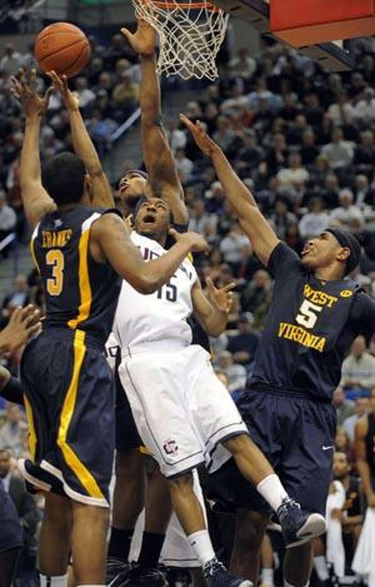 West Virginia's Devin Ebanks, (3), Danny Jennings, center, and Kevin Jones, (5), defend against Connecticut's Kemba Walker during the first half of Monday's game in Hartford. (AP Photo/Fred Beckham)