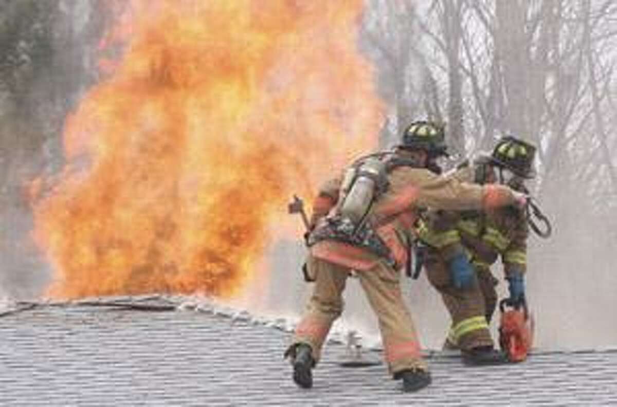 SONJA ZINKE/Register Citizen Torrington fireighters Lt. David Tripp and Kevin Engle vent the roof of a house on fire on Atena Avenue in Torrington Thursday.