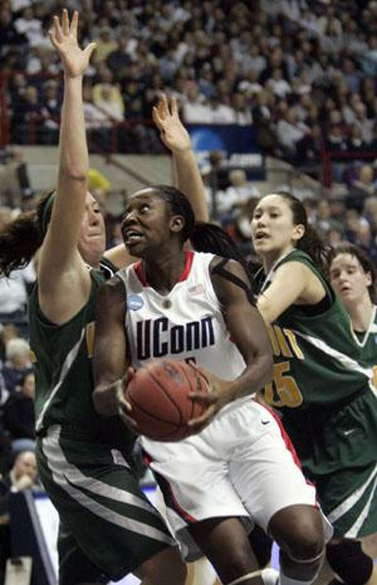 Connecticut's Tina Charles, center, drives in to the basket as Vermont's Amy Rosenkrantsz, left, and Sy Janousek, right, try to stop her during the second half of their NCAA tournament game Sunday in Storrs. UConn defeated Vermont 104-65. Charles was high-scorer for UConn and for the game with 32 points.