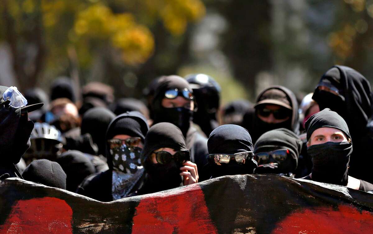 Dozens of masked anarchists stand together after the police left Dr. Martin Luther King Jr. Civic Center park after they arrived with a large group of anti-racist protesters in response to an expected far-right rally that was supposed to be held in the park August 27, 2017 in Berkeley Calif.