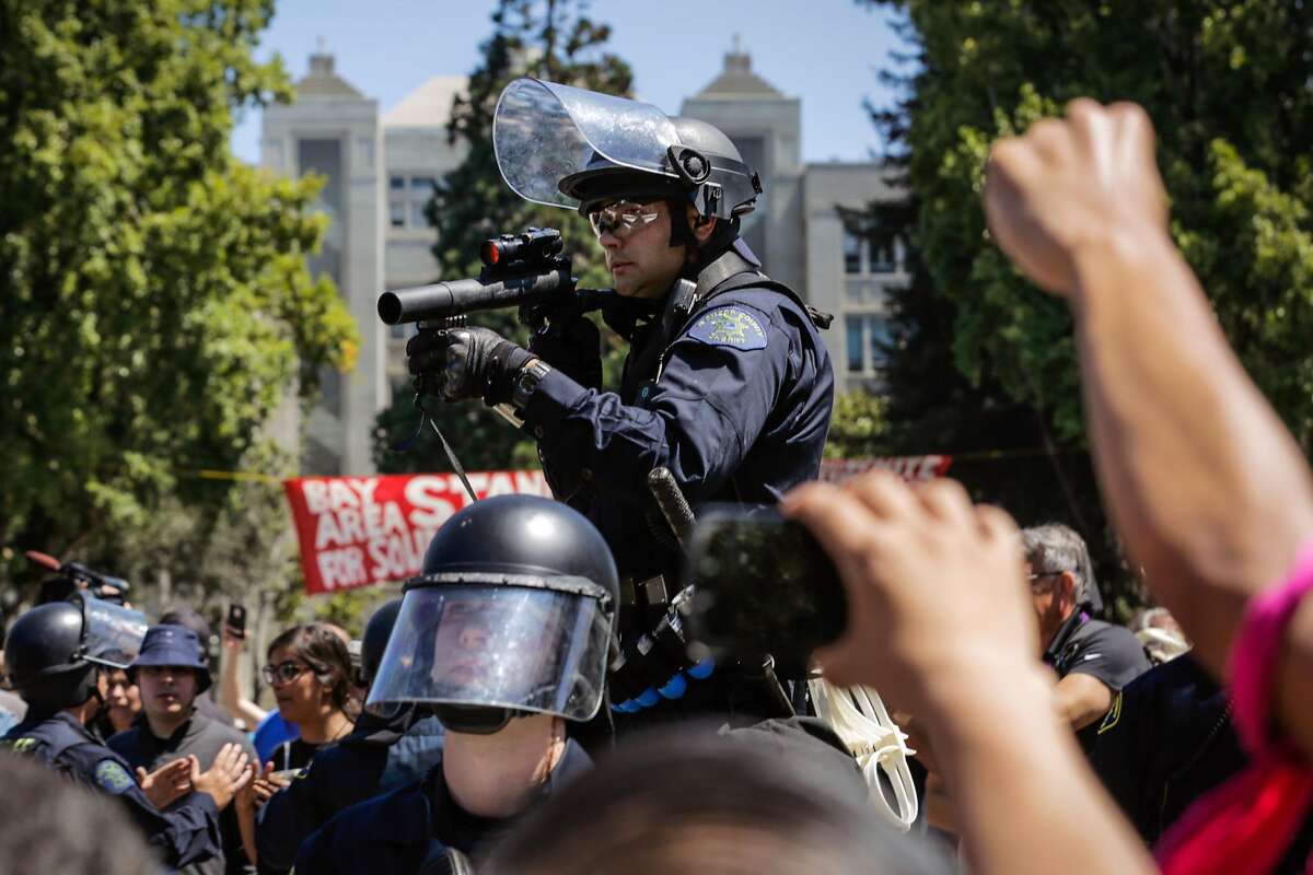 A police officer holds up a tear gas gun at a group of anti-fascist protesters at the corner of Martin Luther King Jr. Way and Allston Way during a clash between protesters in Berkeley, Calif., on Sunday, August 27th, 2017.