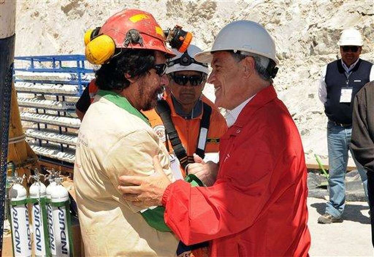 In this photo released by the Chilean Presidential Press Office, Chile's President Sebastian Pinera, back, greets miner Victor Segovia Rojas after his rescue operation from the collapsed San Jose gold and copper mine, near Copiapo, Chile, Wednesday, Oct. 13, 2010. (AP Photo/Jose Manuel de la Maza, Chilean Presidential Press Office)