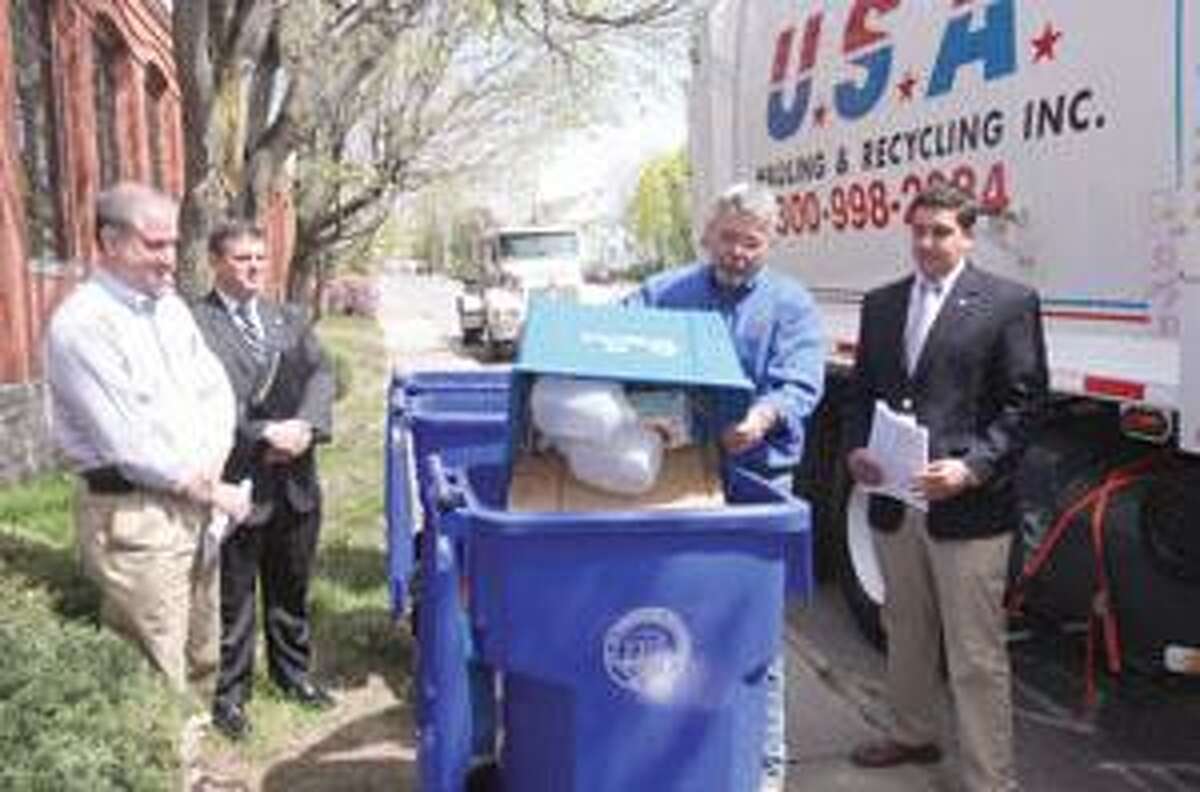 SONJA ZINKE/Register CitizenFrom left, Torrington Director of Public Works, Jerry Rollett and Director of Public Affairs for Connecticut Resources Recovery Authority Paul Nonnemacher along with Torrington Mayor Ryan Bingham, right watch as USA Operation Manager Jim Rockwell shows how the new single stream recycling will affect the public Wednesday in front of City Hall on Field Street. Purchase a glossy print of this photo and more at ww.registercitizen.com