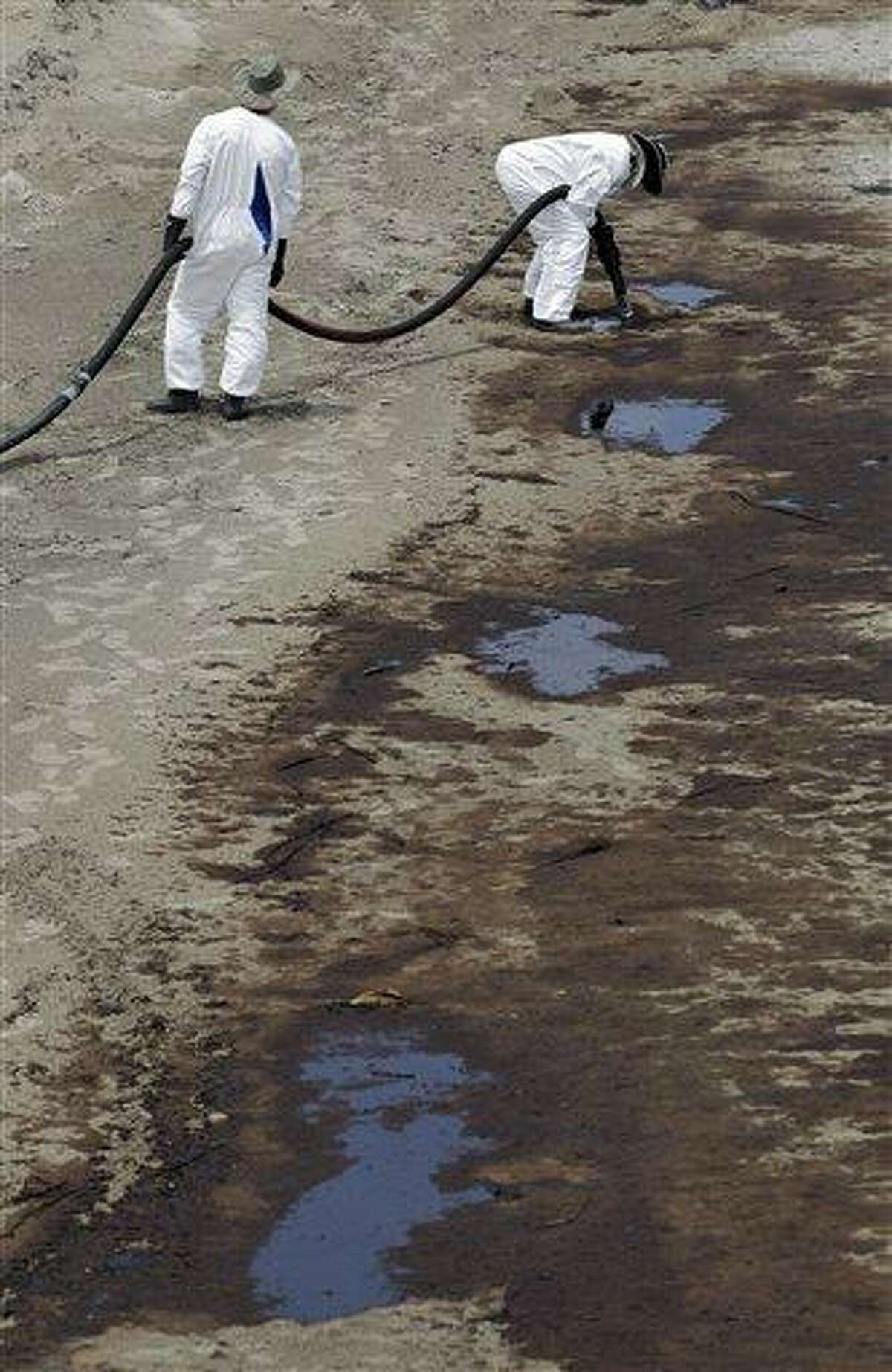 A worker uses a suction hose to remove oil that has washed ashore from the Deepwater Horizon spill, Sunday, June 6, 2010 in Grand Isle, La.. (AP Photo/Eric Gay)