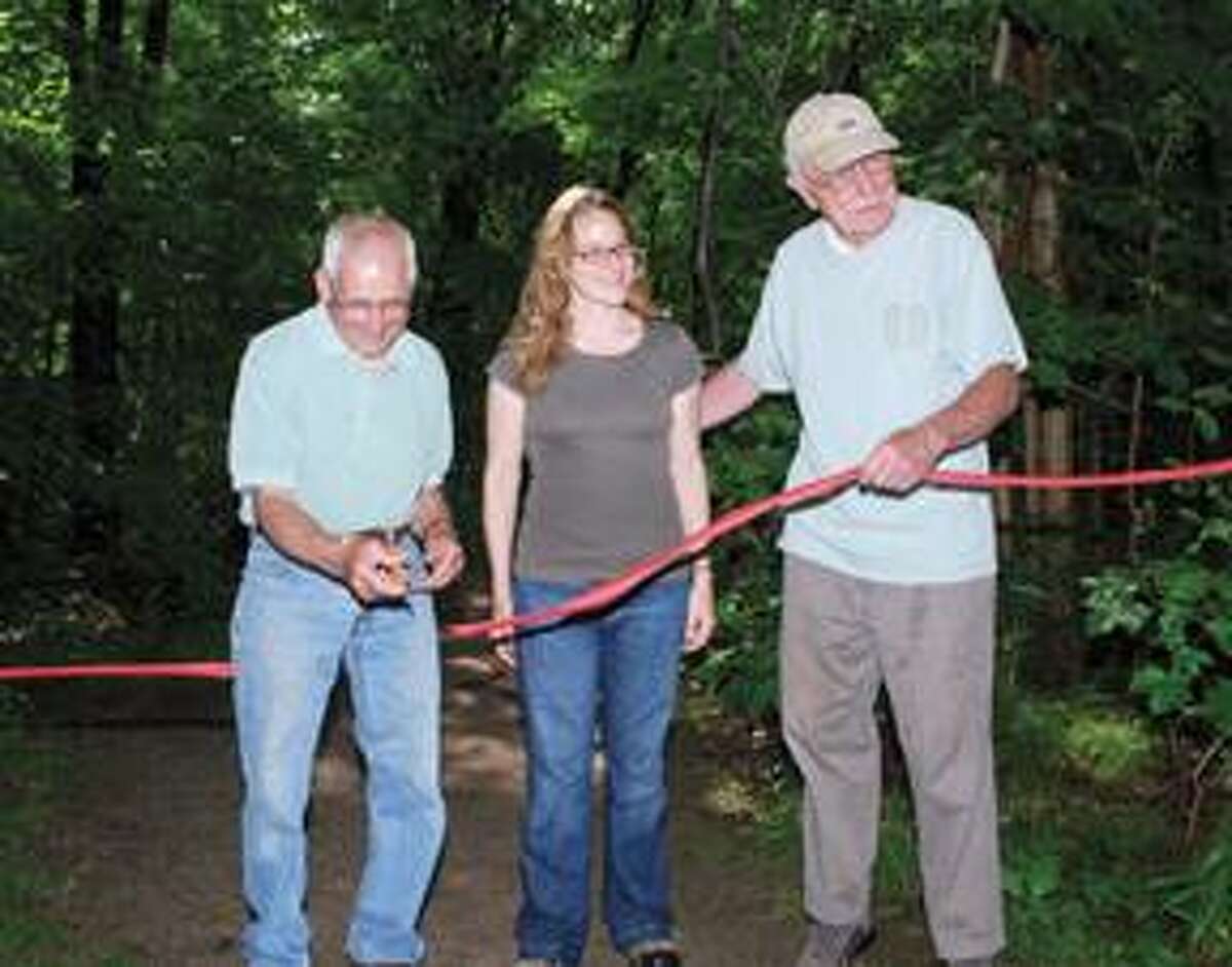 RONALD DeROSAFirst Selectman Frank Chiaramonte, left, cuts the ribbon that dedicates the town of Harwinton's new acquisition of the 65 acres of the Carros Property, which will remain a preserve. Standing in the middle is Lisa Bassani, project manager, and to the right is Hert Etter, chairman of the town's Open Space Committee.