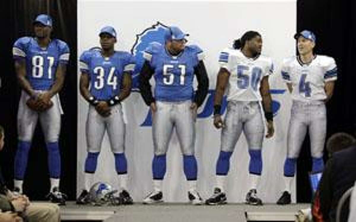 From left, Detroit Lions wide receiver Calvin Johnson (81) running back Kevin Smith (34), center Dominic Raiola (51), linebacker Ernie Sims (50) and place kicker Jason Hanson (4) unveil their new team uniforms in Madison Heights, Mich., Monday. The team's comprehensive new brand includes a new logo, new uniforms and other branding elements. The Lions have the No. 1 pick in the draft. (AP Photo/Paul Sancya)