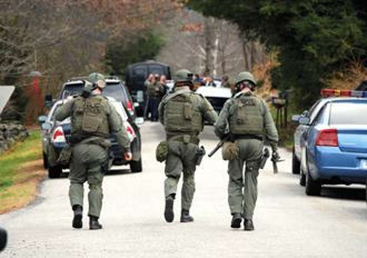 RONALD DEROSA/Register Citizen Tactical unit officers from the state police walk towards the scene of a standoff between John Lavoie, 16 E. Litchfield Road South, and the state police. Police labored throughout the day Tuesday to get Lavoie, who was armed, out of his house. He is suspected for shooting his wife, Shelly.