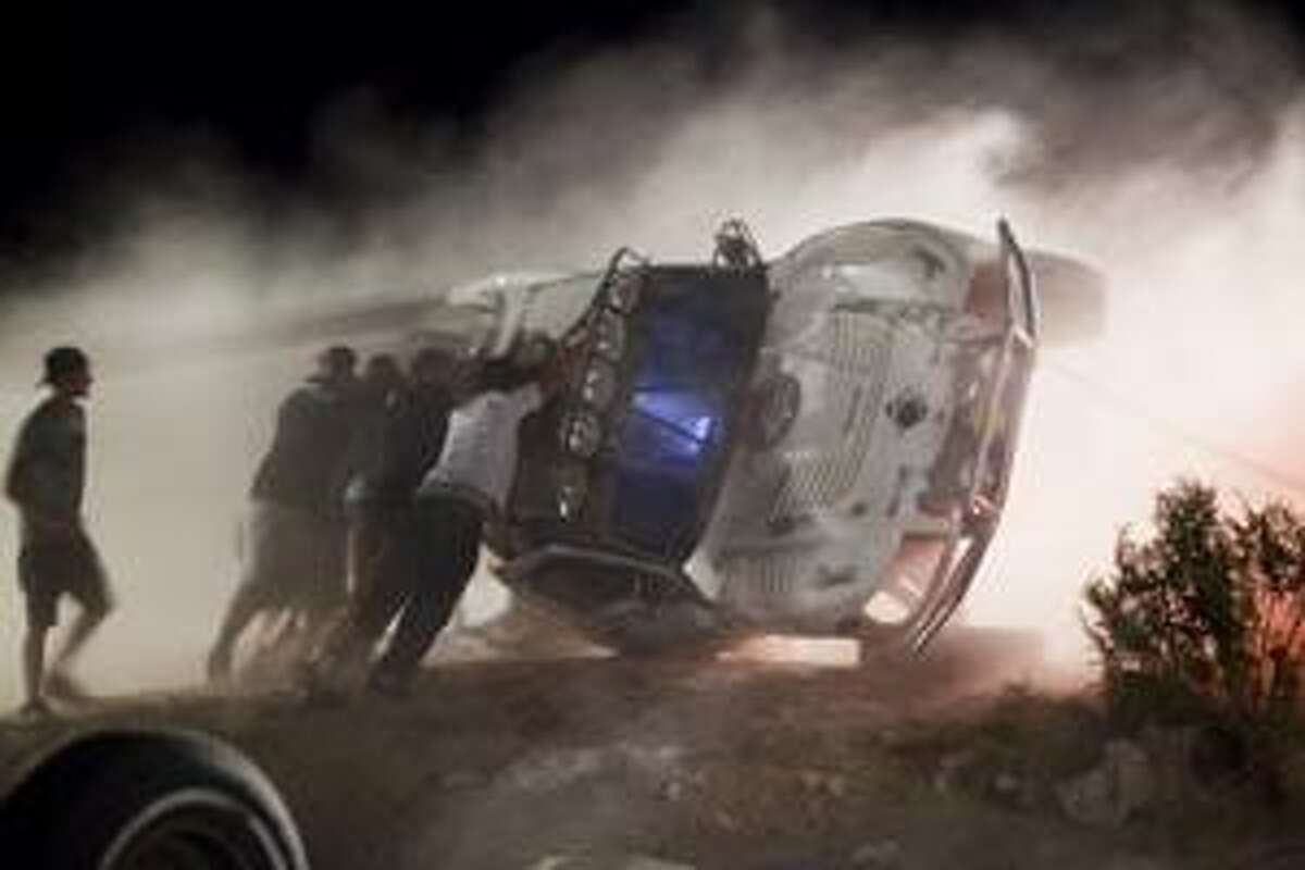 Workers push an overturned off-road race truck upright Sunday, after it went out of control and ran into a crowd of spectators during a race in Lucerne Valley, Calif., on Saturday. At least eight people were killed during the incident about 100 miles east of Los Angeles.(AP Photo/Francis Specker)