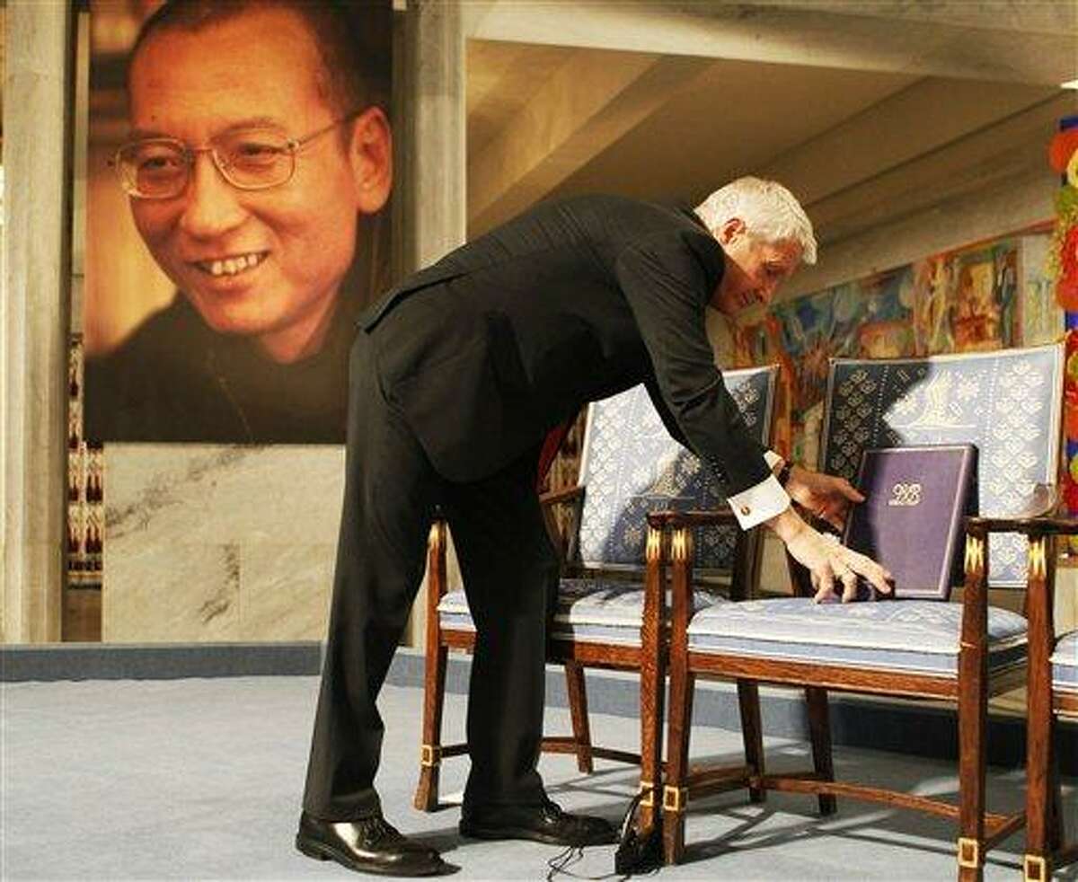 Chairman of the Norwegian Nobel Committee Thorbjoern Jagland places the Nobel diploma and Nobel medal on the empty chair during the ceremony in Oslo City Hall Friday Dec. 10, 2010 to honour in absentia this years Nobel Peace Prize winner, jailed Chinese dissident Liu Xiaobo. (AP Photo Heiko Junge, pool)