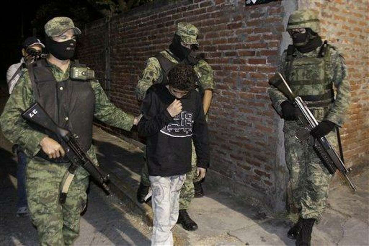 Mexican army soldiers escort a 14-year-old suspected of working as a killer for a drug cartel in the city of Cuernavaca, Mexico, Friday Dec. 3, 2010. The much-rumored alleged young assassin nicknamed "El Ponchis" was captured late Thursday at the airport in Cuernavaca with his 16-year-old sister as they were trying to catch a flight to Tijuana and flee the country to San Diego.(AP Photo/Antonio Sierra)
