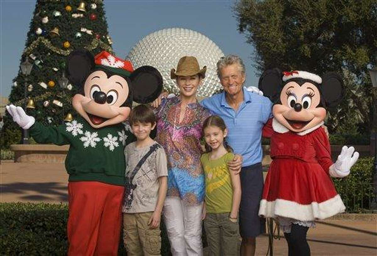 In this publicity image released by Disney, Mickey Mouse and Minnie Mouse pose with actors Catherine Zeta-Jones and Michael Douglas and their children, Dylan, 10, left, and Carys, 7, in front of the Epcot theme park Christmas tree in Lake Buena Vista, Fla., on Wednesday, Nov. 24, 2010. (AP Photo/Disney, Kent Phillips)