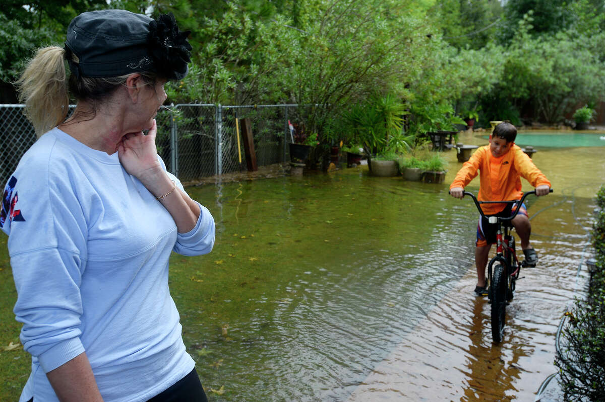 Lisa Sanders watches as her 10-year-old grandson, Branson Blanchard, rides his bike through her flooded backyard in Vidor on Monday. Rain from Tropical Storm has brought heavy rains to the region. Photo taken Monday 8/28/17 Ryan Pelham/The Enterprise