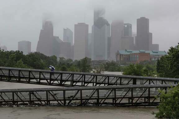 People walk over the Rosemont Pedestrian Bridge to look at a flooded Buffalo Bayou as Tropical Storm Harvey continues to dump rain over downtown Houston Tuesday, Aug. 29, 2017.